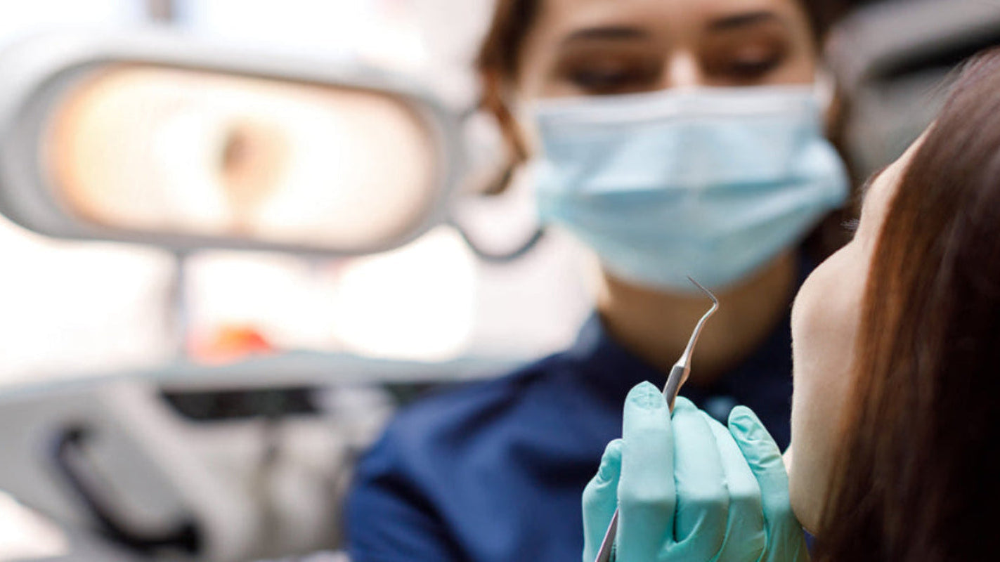 Dentist examining a patient's teeth with dental tools in a clinical setting